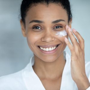 Vrouw met donkere huid die gezichtsverzorging toepast